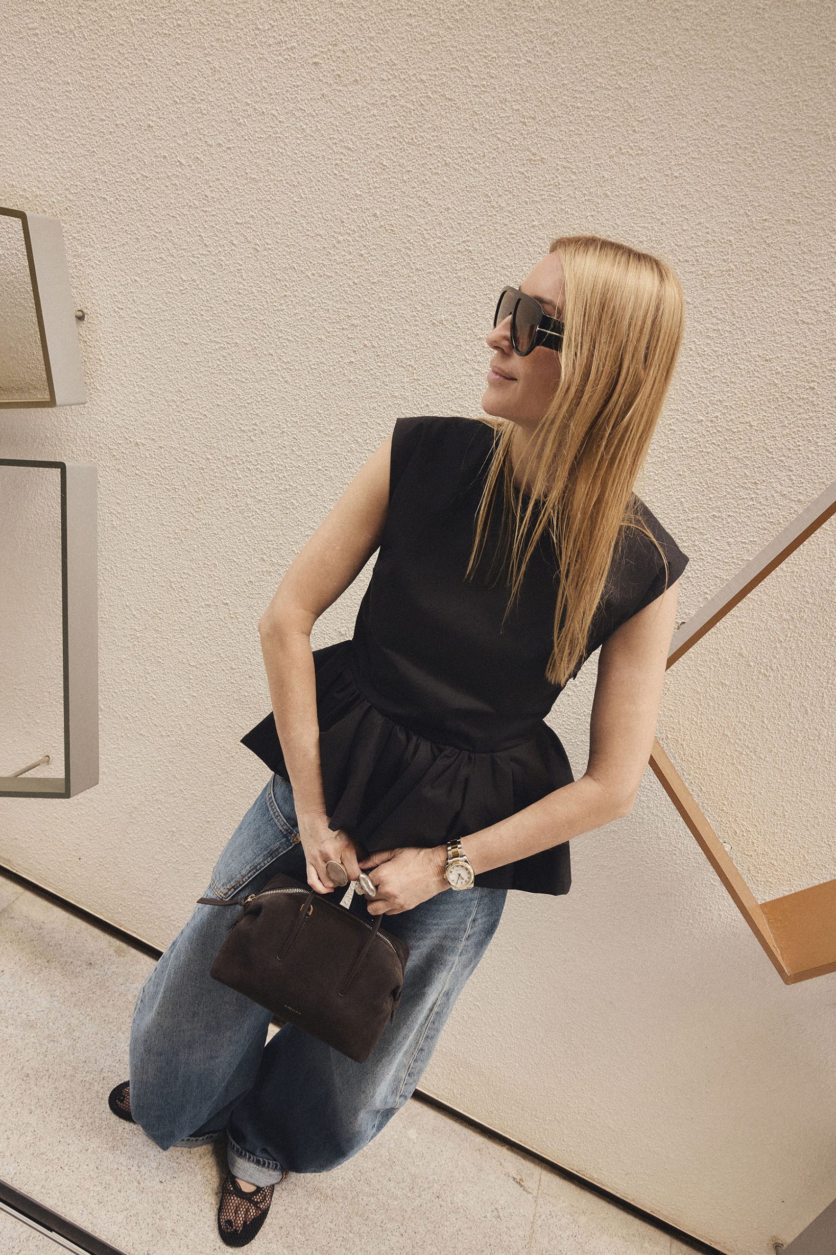 Detalle del bolso Stockholm de DeMellier London en ante chocolate con top peplum y denim amplio