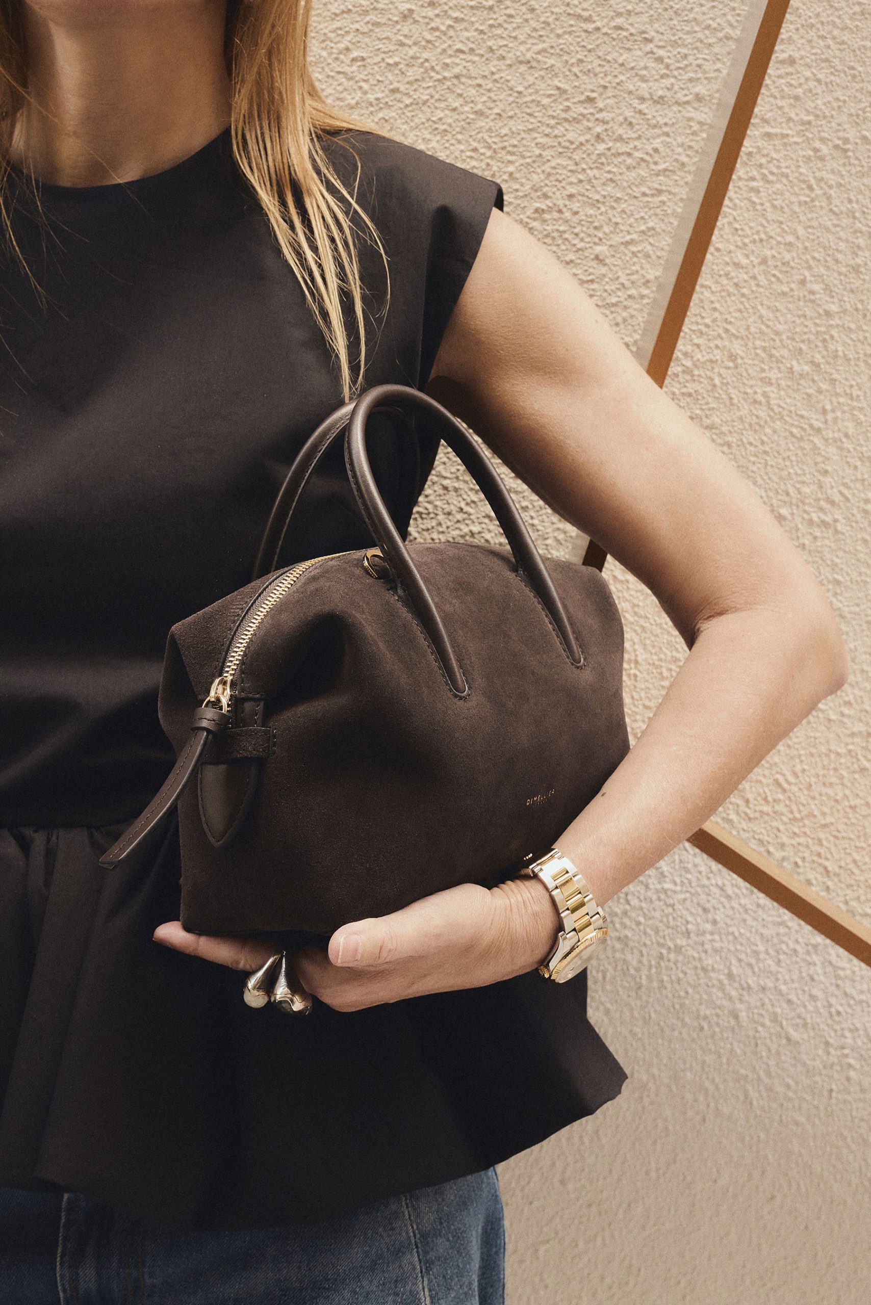 Primer plano del bolso Stockholm de DeMellier London en ante chocolate con acabado mate y diseño depurado